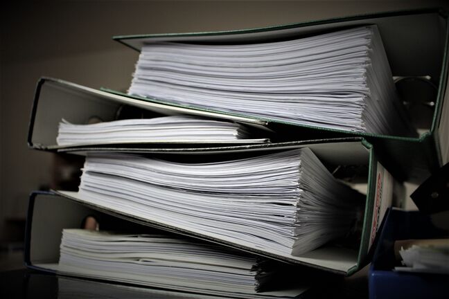 Stacked binders of paper tax records affected by new UAE record keeping rules for scanned documents
